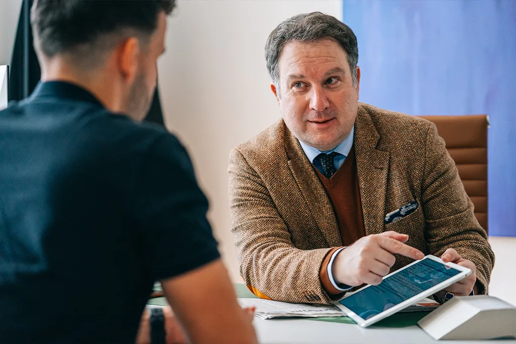 Professor Dr. iur. Peter Kreuz erklärt rechtliche Inhalte auf Tablet im Mandantengespräch