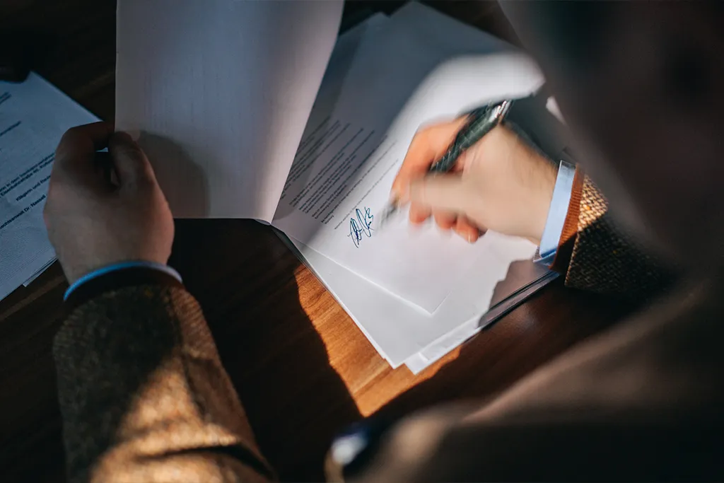 Professor Dr. iur. Peter Kreuz unterschreibt Vertragsdokumente zum Wirtschaftsrecht.